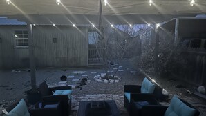 Ein Außenbereich mit Tischen und Stühlen, eine überdachte Terrasse und Lichterketten.
