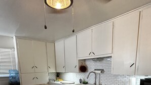 Eine Küche mit weißen Schränken, einer Holztheke und einer Pendelleuchte.