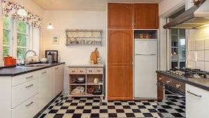 A kitchen with a checkered floor, wooden cabinets, a refrigerator, and a stove. - 5 Person Holiday Home in Laeso (Læsø)