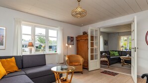 A cozy living room with a grey sofa, a wicker chair, and a glass coffee table. - 5 Person Holiday Home in Laeso (Læsø)
