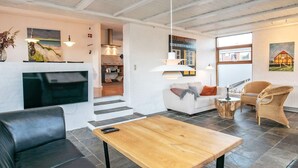 Un salon moderne avec une cheminée, un canapé, une table basse et un coin repas.