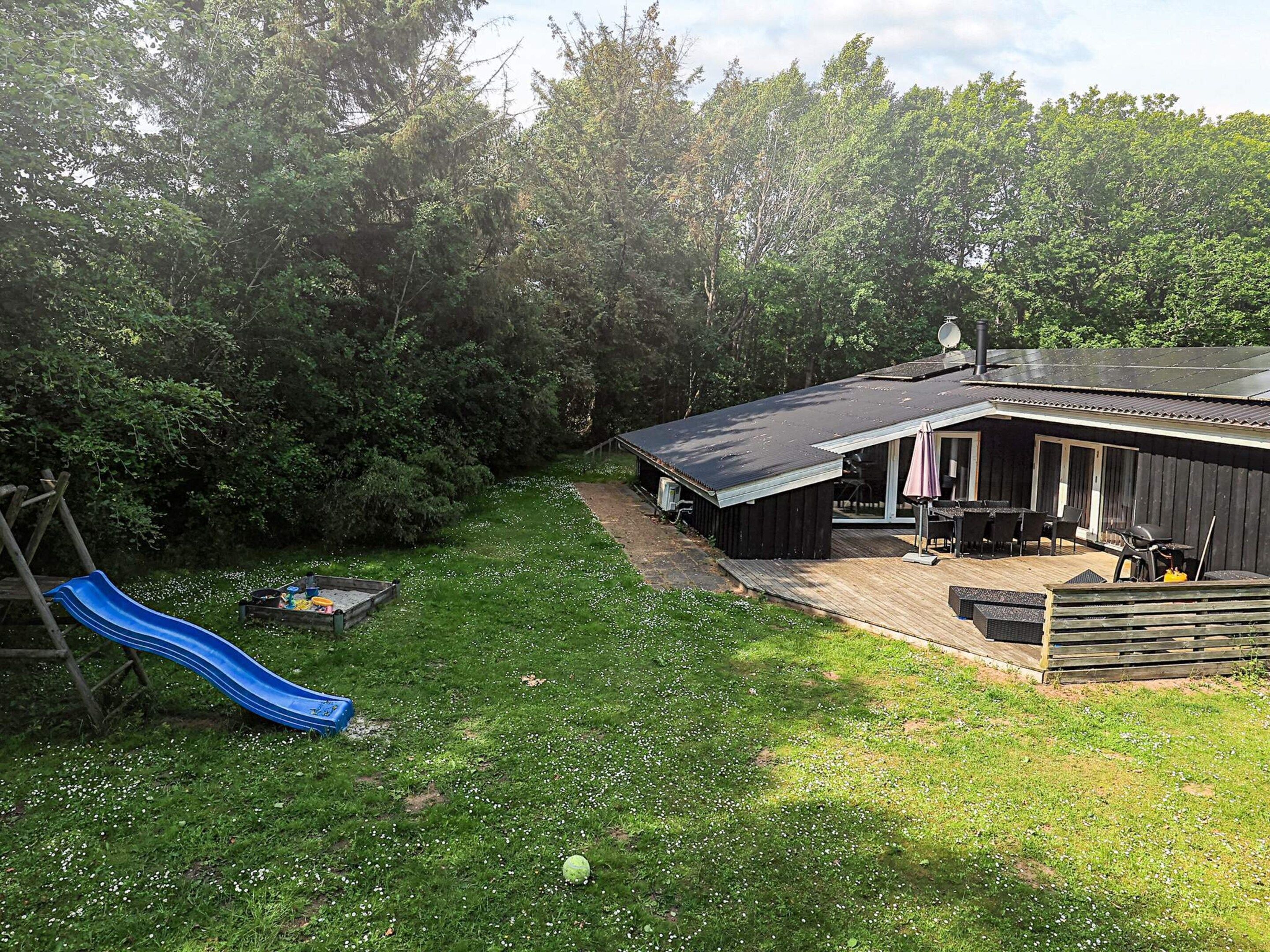 A backyard with a blue slide, a barbecue area, and a covered patio.