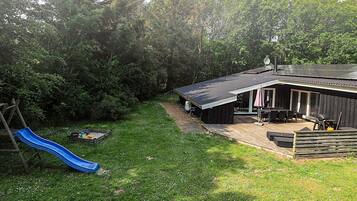 En baghave med blå rutsjebane, grillområde og overdækket terrasse.