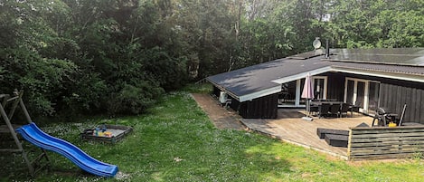 A backyard with a blue slide, a barbecue area, and a covered patio.