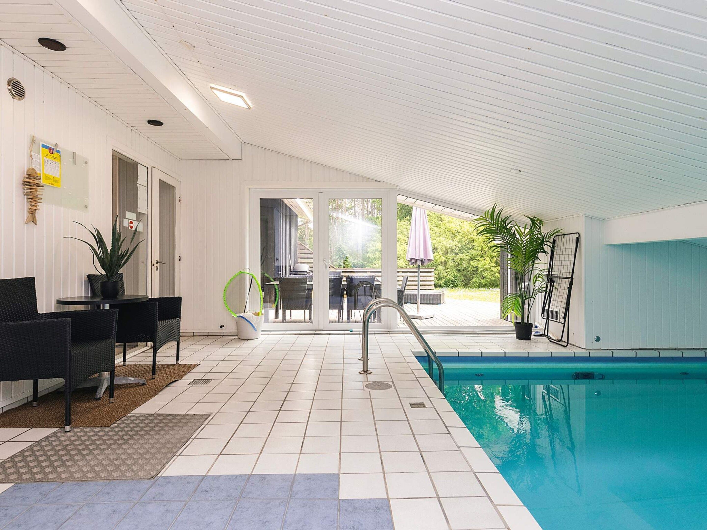 Zona de piscina con porche cubierto, mobiliario exterior y vistas al exterior.