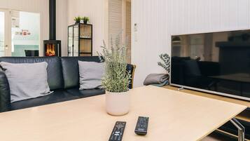 En moderne stue med en sort lædersofa, et træ sofabord, et stort fladskærms TV og en pejs.