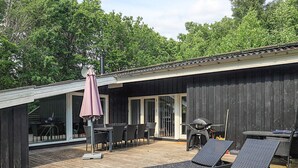 A modern outdoor deck with a dining area, lounge chairs, and a barbecue grill. - 8 Person Holiday Home in Albaek (Aalbaek)