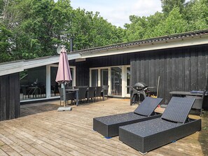 A modern outdoor deck with a dining area, lounge chairs, and a barbecue grill. - 8 Person Holiday Home in Albaek (Aalbaek)