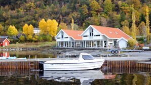 A white boat docked at a pier with a house in the background. - 8 Person Holiday Home in Jelsa (Suldal)