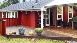 A red building with a covered patio, a chimney, and a large window. - 6 Person Holiday Home in Hals (Hals)