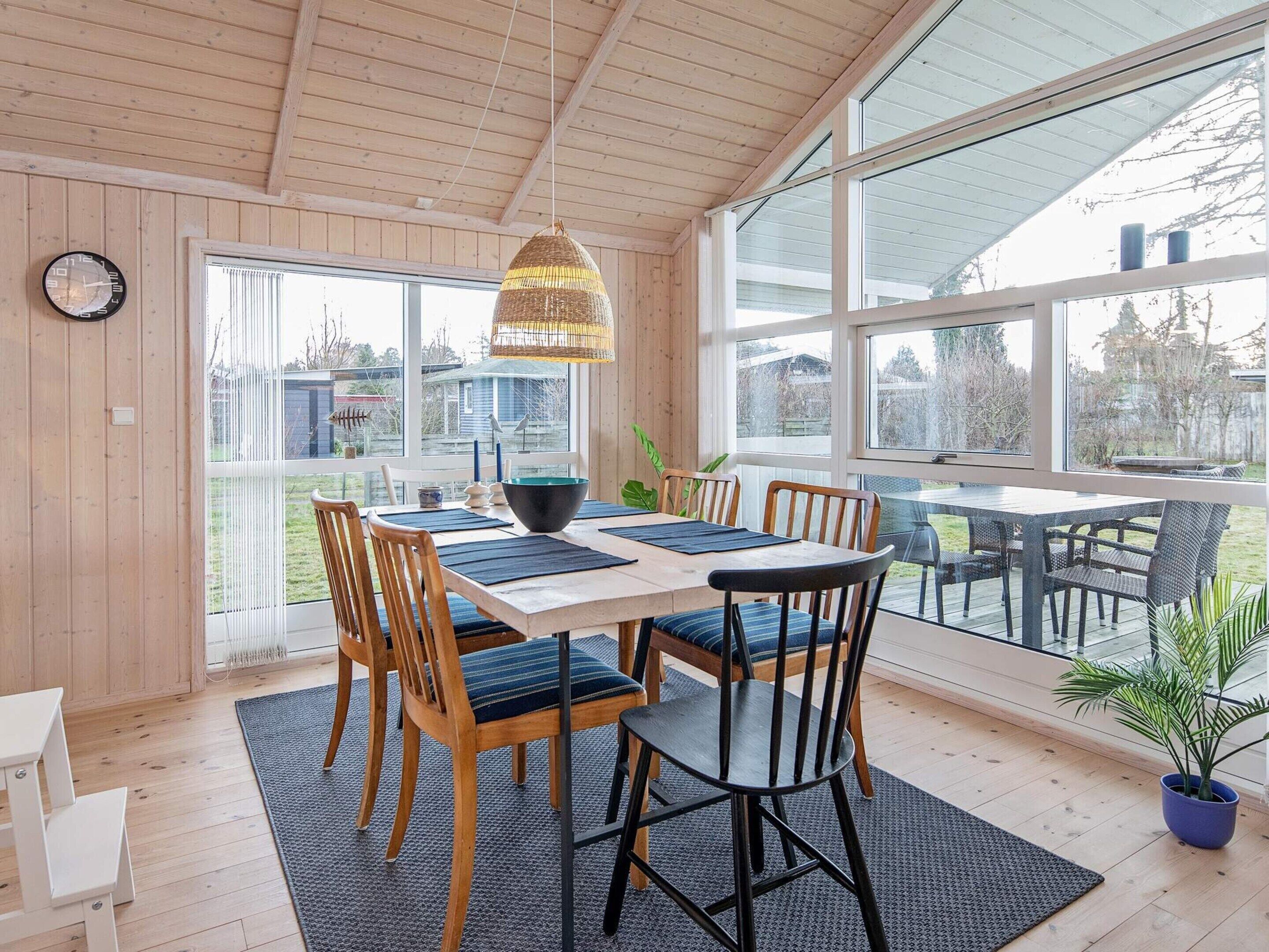 A dining area with a wooden table, chairs, and a hanging light fixture.