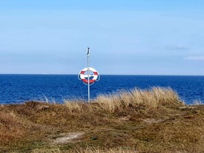 A lifebuoy sign on a grassy cliff overlooking the ocean.