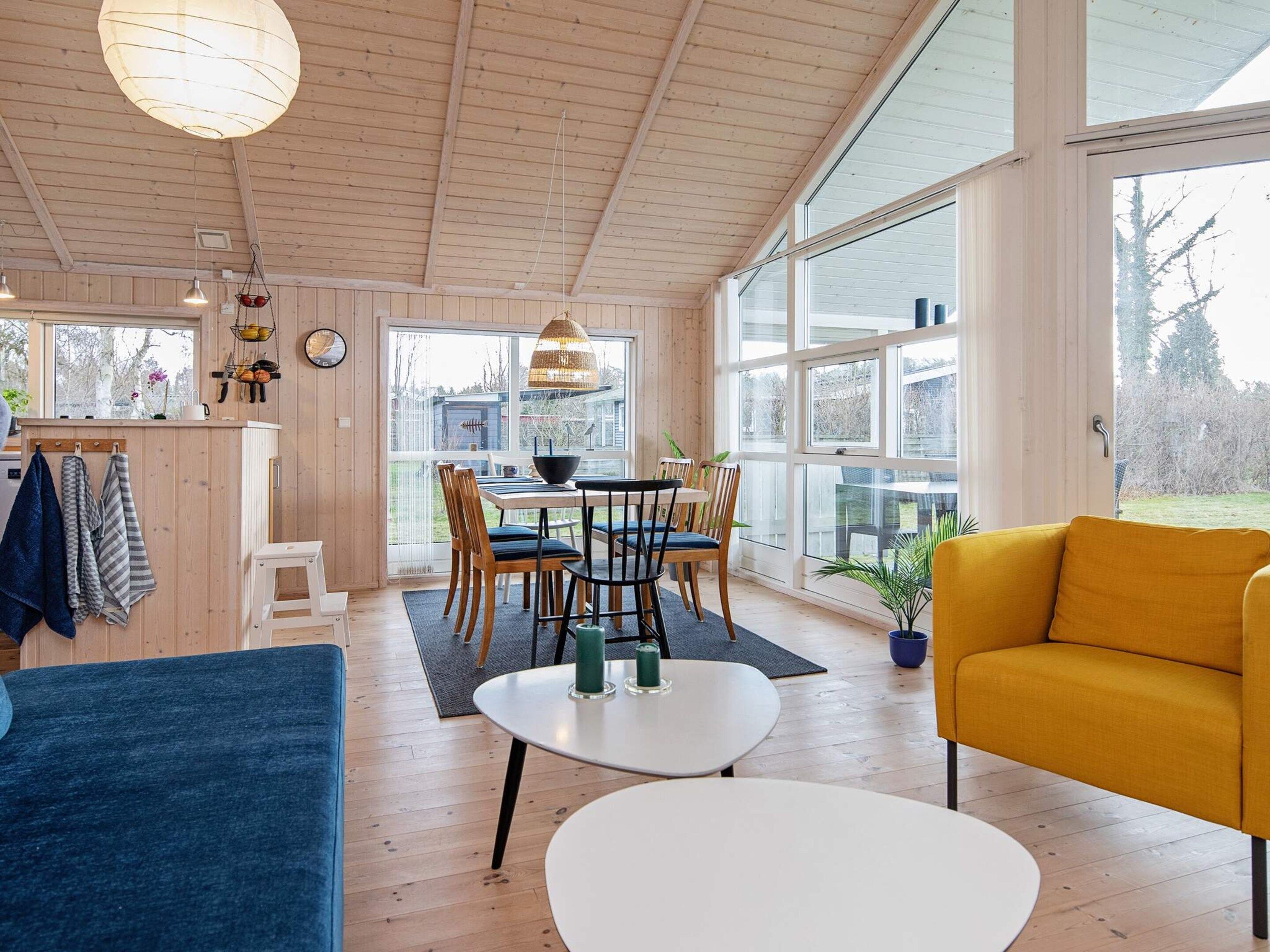 Un amplio salón con mesa de comedor, sillas, un sofá y un sillón amarillo.