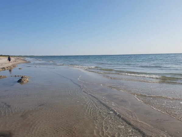 A beach with clear water and a person walking. - 4 Star Holiday Home in Vaeggerlose (Vaeggerlose)