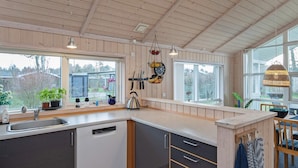 A modern kitchen with wooden cabinets, a dishwasher, and a window overlooking a garden. - 4 Star Holiday Home in Vaeggerlose (Vaeggerlose)
