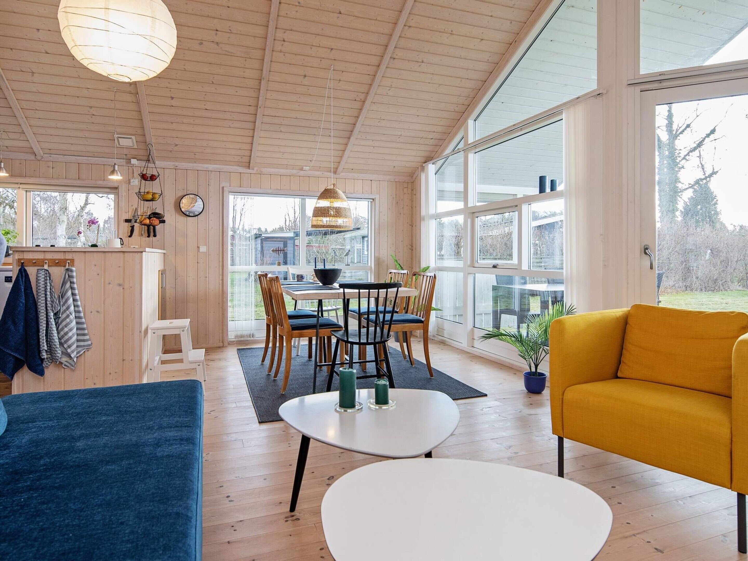 A spacious room with a dining area, a sofa, and a large window providing a view of the outdoors.