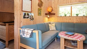 A wooden interior with a blue sofa, a small table with a checkered tablecloth, and a globe on the wall. - 6 Person Holiday Home in Hovborg (Hovborg)