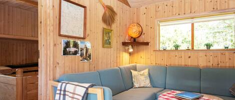 A wooden interior with a blue sofa, a small table with a checkered tablecloth, and a globe on the wall.