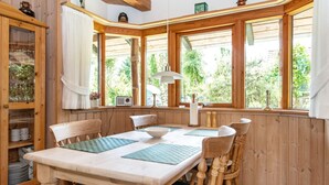 A wooden-paneled room with a dining table, chairs, and large windows offering a view of greenery outside. - 6 Person Holiday Home in Hovborg (Hovborg)