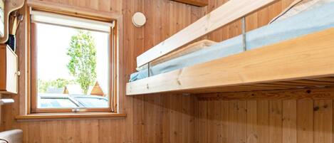 A wooden bunk bed room with a window, a radiator, and a plaid chair.