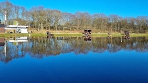A calm lake with boats, a small dock, and a building with a sign. - 6 Person Holiday Home in Hovborg (Hovborg)