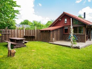 A wooden cabin with a red roof, a picnic table, and a bicycle.