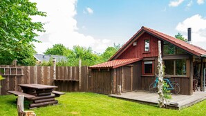 A wooden cabin with a red roof, a picnic table, and a bicycle. - 6 Person Holiday Home in Hovborg (Hovborg)