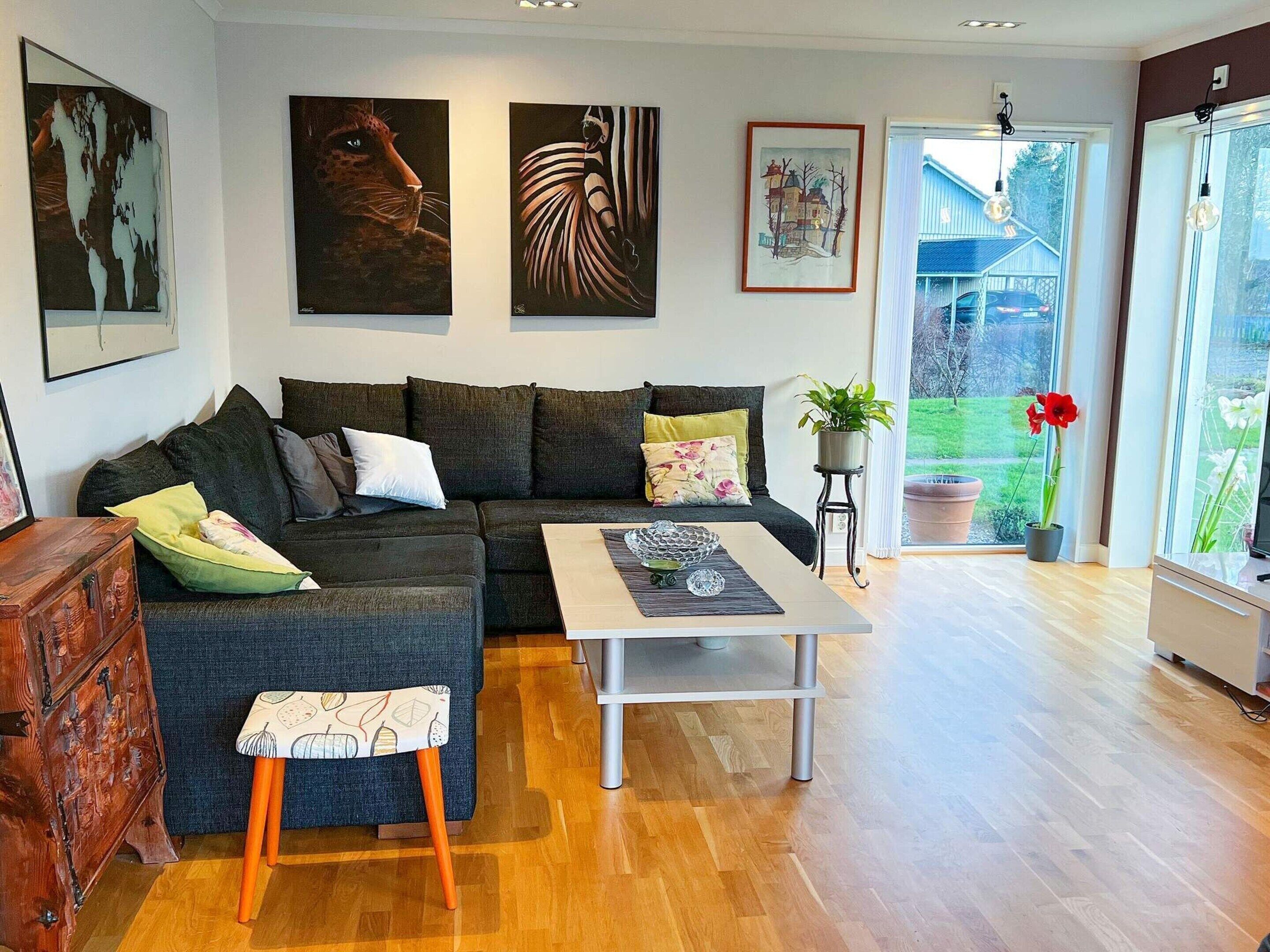 A modern living room with a sectional sofa, a coffee table, and artwork on the walls.