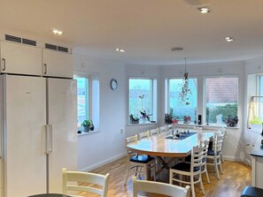 A modern kitchen with a central island, white cabinetry, and large windows.