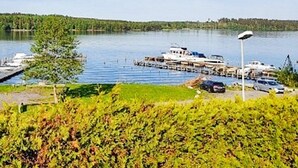 Un puerto deportivo con barcos amarrados, cielo despejado y una costa cubierta de bosque.