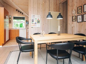A wooden interior with a dining table, chairs, a refrigerator, and a window overlooking greenery. - 6 Person Holiday Home in Hemmet (Hemmet)