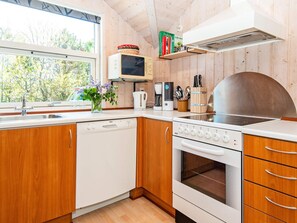 A kitchen with wooden cabinets, a dishwasher, a stove, and a microwave. - 6 Person Holiday Home in Hemmet (Hemmet)