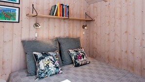 Una habitación acogedora con una cama, dos almohadas, una estantería con libros y cuadros en la pared.