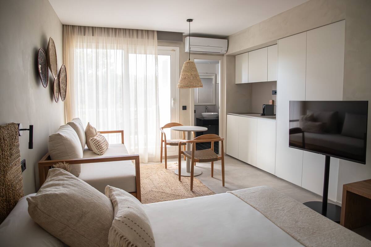 A modern, well-lit living room with a sofa, a small dining table, and a TV.