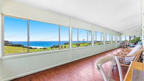 A room with large windows offering a view of the ocean and greenery. - 12 Bluewater Drive Narooma (Narooma)