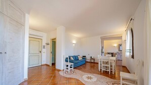 A spacious living area with a blue sofa, white dining set, and a tiled floor. - Casa Nadia by Wonderful Italy (Olbia)