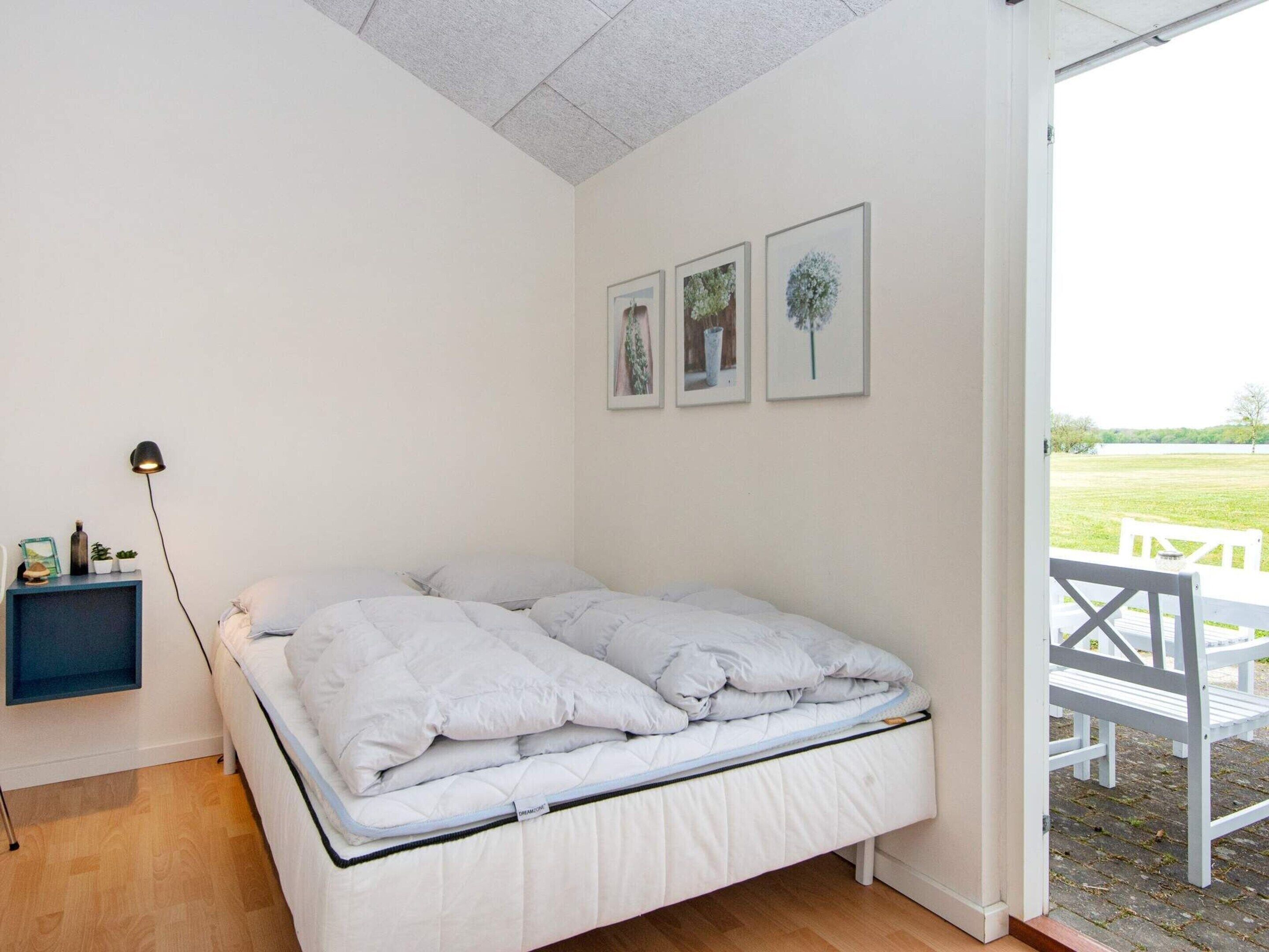 Une chambre à coucher avec un lit, une table de chevet avec une lampe et trois tableaux encadrés accrochés au mur.