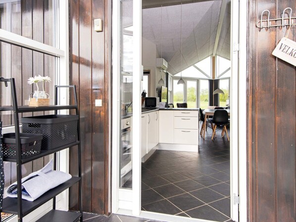 A modern kitchen with white cabinets, a black tiled floor, and a dining area with a table and chairs.