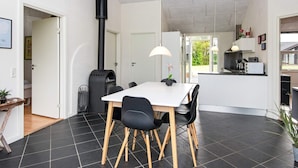 A modern kitchen with a white countertop, black chairs, and a black stove. - 4 Star Holiday Home in Ansager (Ansager)