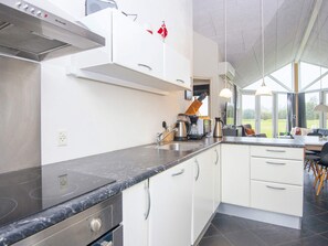 A modern kitchen with white cabinets, a black countertop, and a large window offering a view of the outdoors. - 4 Star Holiday Home in Ansager (Ansager)