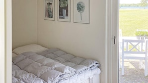 Un dormitorio con cama, una puerta a un espacio exterior y tres cuadros en la pared.