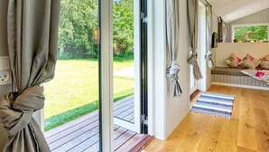 Ein Zimmer mit einer Schiebetür zu einer Holzdiele, einer Bank mit Kissen und einem kleinen Teppich.