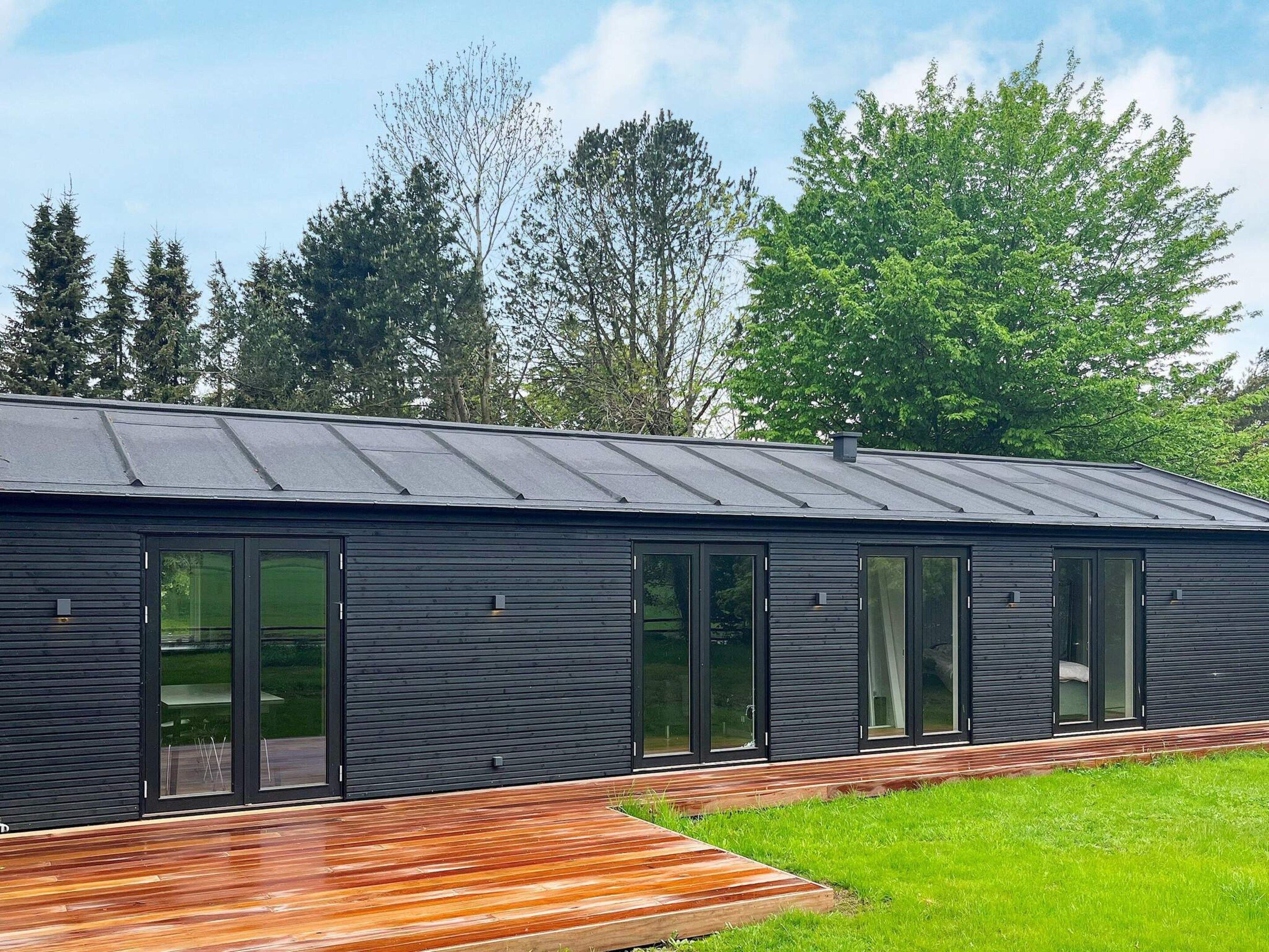 A modern building with a flat roof, large windows, and a wooden deck.