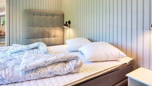 Ein Schlafzimmer mit einem Bett, einem Kopfteil, einem Nachttisch und einer Wandlampe.