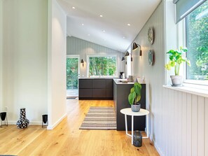 Une cuisine moderne avec une grande fenêtre, un plancher en bois et une petite table ronde agrémentée d’une plante en pot.