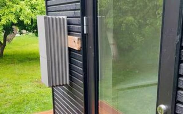 A modern building with a glass door, a metal railing, and a wooden deck.