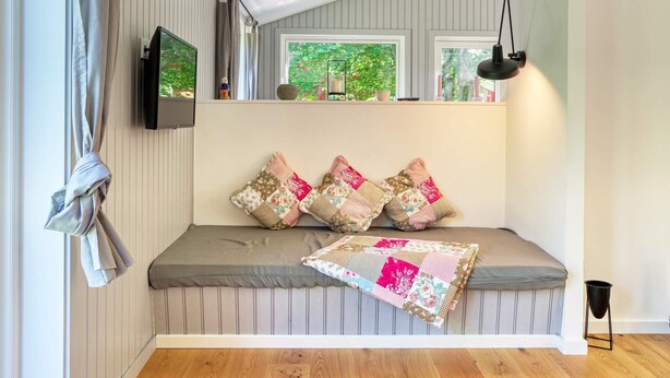 Ein gemütliches Zimmer mit eingebautem Sitzplatz, einem Flachbildfernseher und einem Fenster mit Blick auf Grünflächen.
