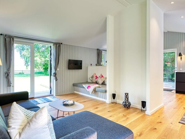 A modern living room with a sofa, a small table, and a TV mounted on the wall.