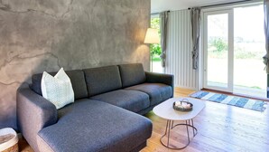 Ein modernes Wohnzimmer mit einem grauen Sofa, einem kleinen runden Tisch und einer Lampe.