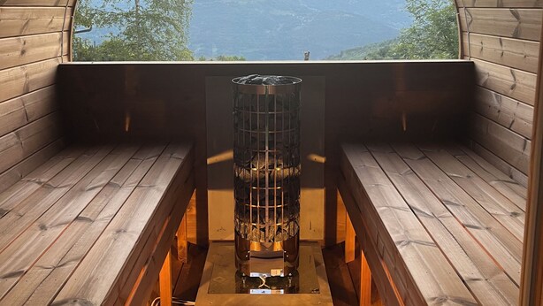A wooden cabin with a curved ceiling and a central fireplace. - Chalet + sauna with panoramic views in beautiful surroundings (Albiez-le-Jeune)